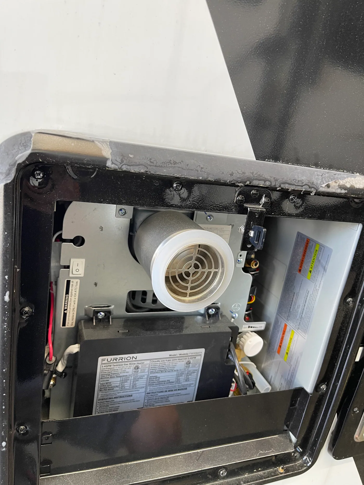 Furrion 2.4 GPM tankless gas RV water heater with its exterior access door open