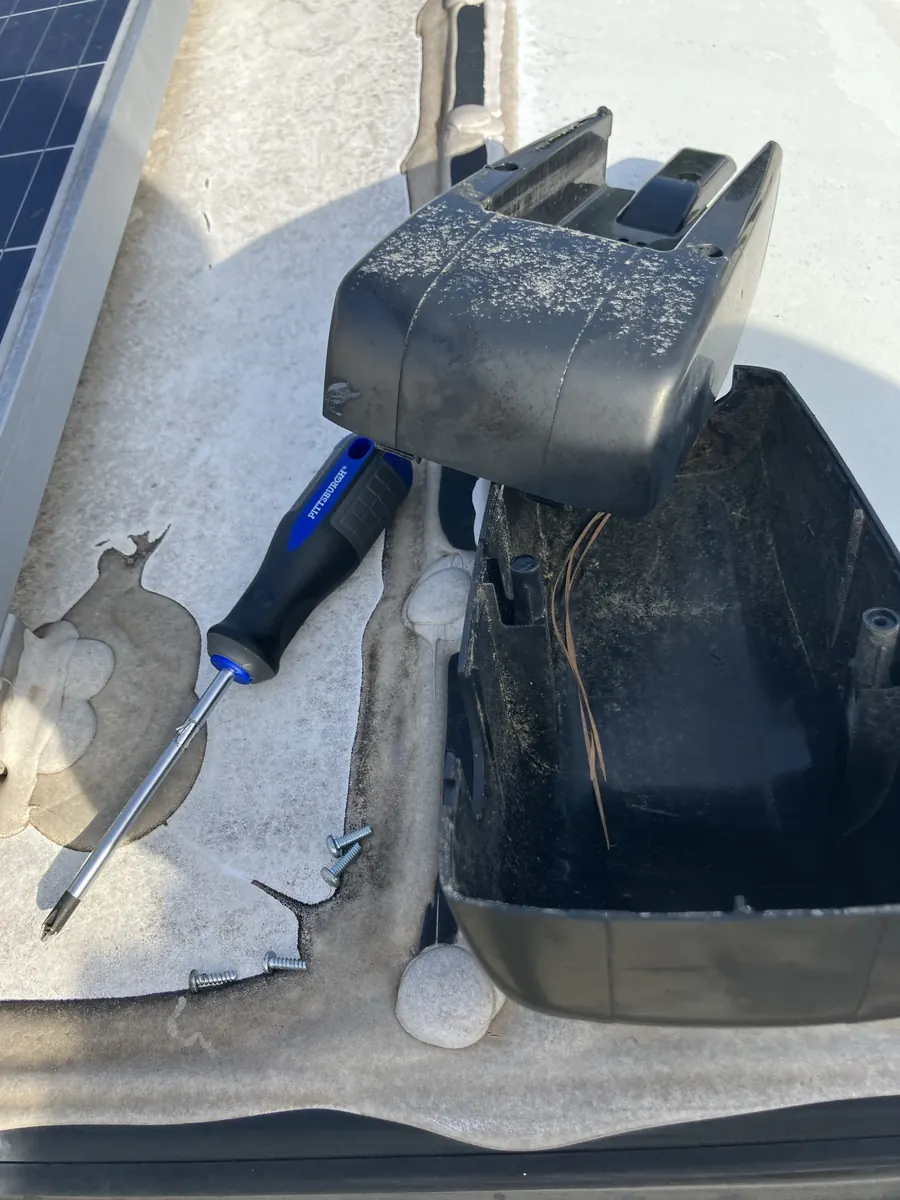 Plastic drive-head cover removed from an RV power awning with its screws set aside