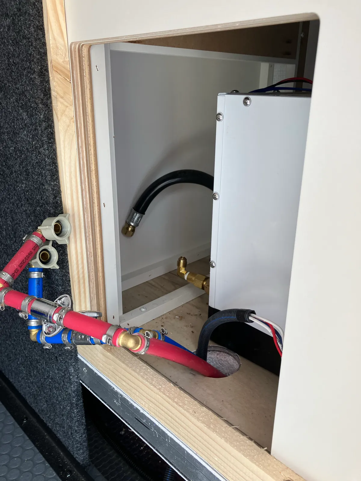 Water lines, LP hose and electrical wiring disconnected behind a Brinkley tankless water heater