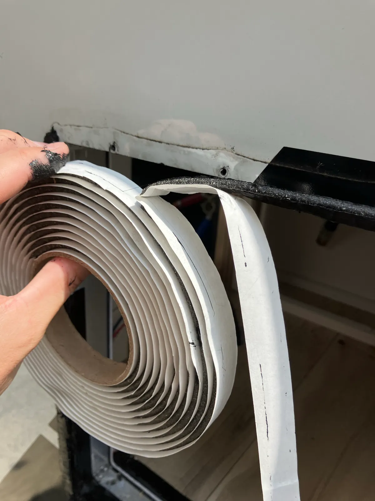 One-inch butyl tape being applied behind an RV tankless water heater exterior flange