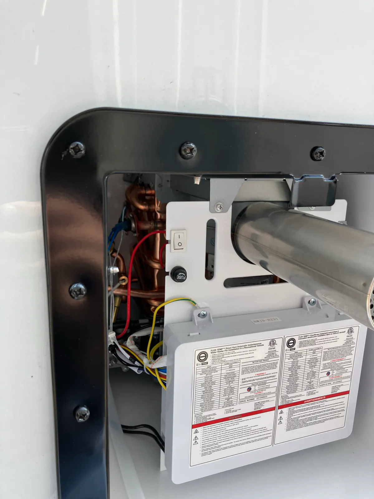 Replacement RVMP Flex Temp tankless water heater secured in the exterior opening of a Brinkley Model Z