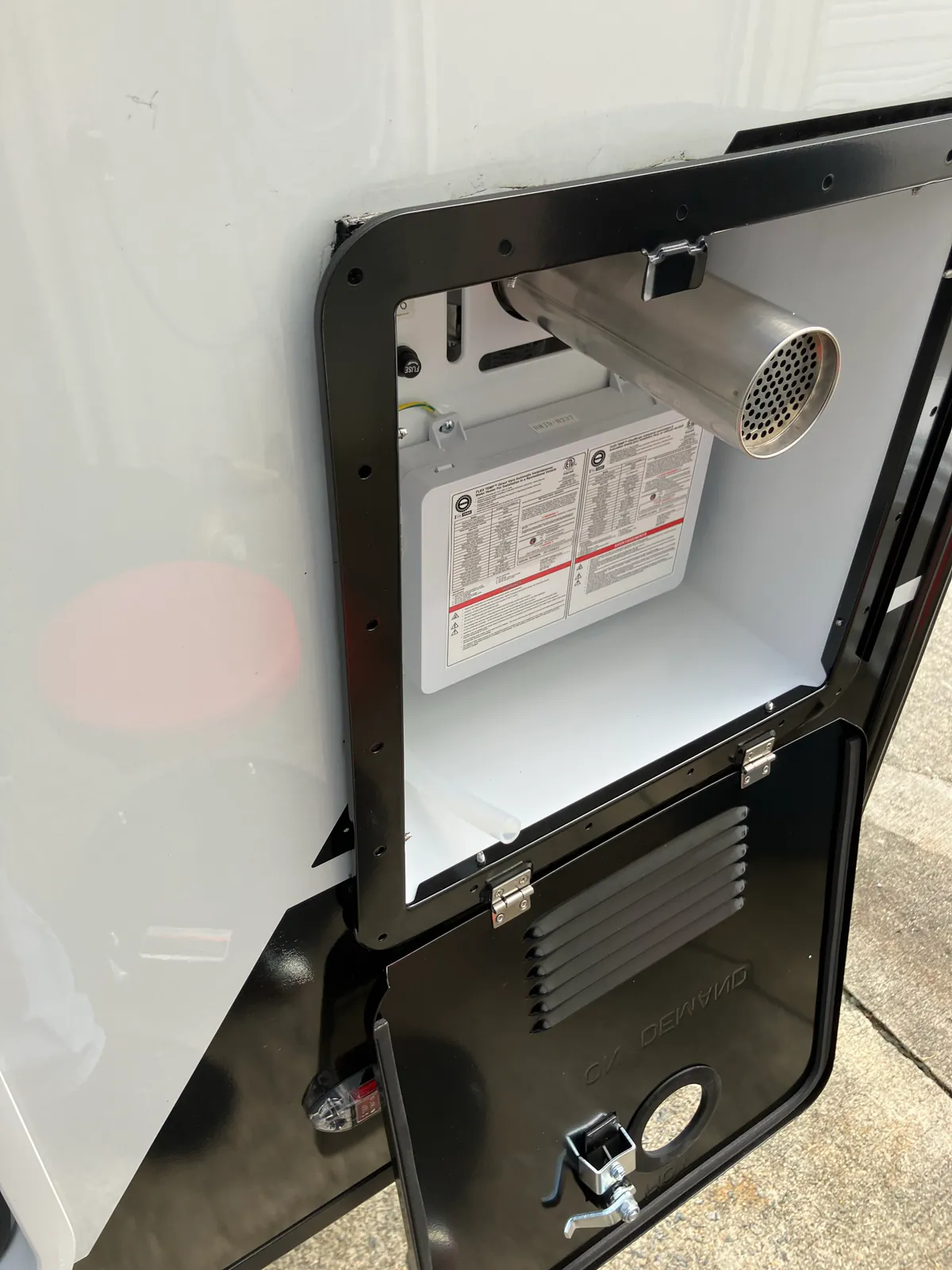 New RVMP Flex Temp tankless water heater seated in an RV exterior wall opening before all flange screws are installed